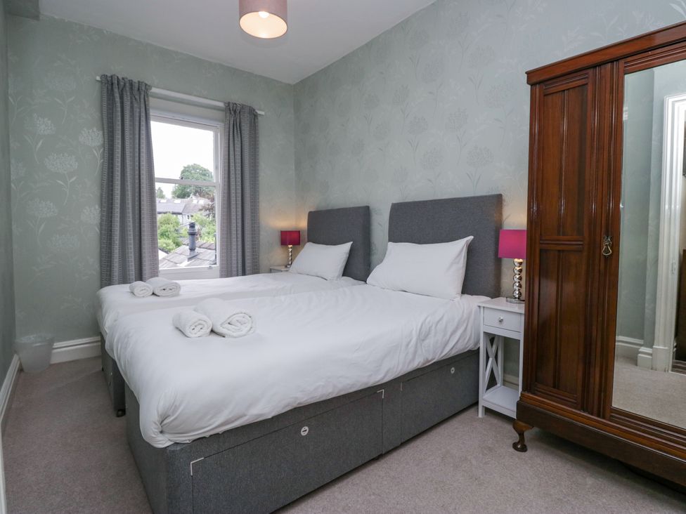 A bedroom with two beds and a wardrobe at 14 Castle Garth in Kendal