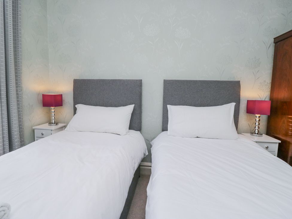 A bedroom with two single beds and bedside tables at 14 Castle Garth Kendal