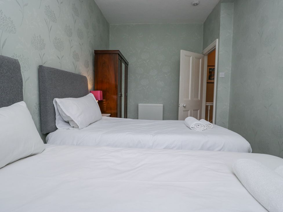A bedroom with two beds and a wardrobe at 14 Castle Garth, Kendal