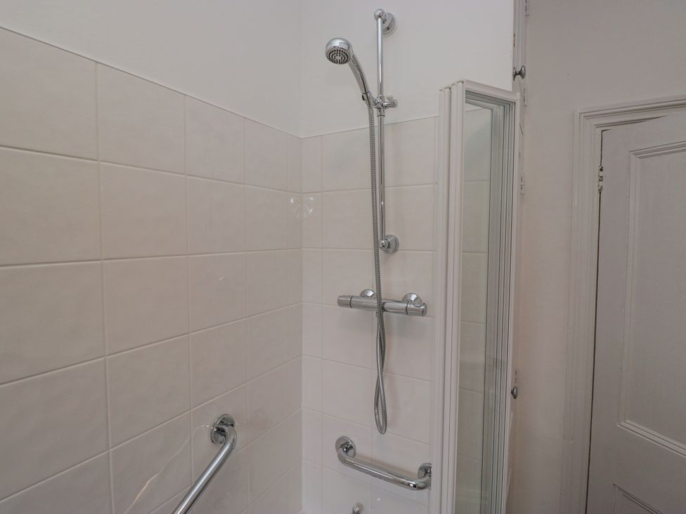 A shower with grab bars and tiled walls at 14 Castle Garth Kendal