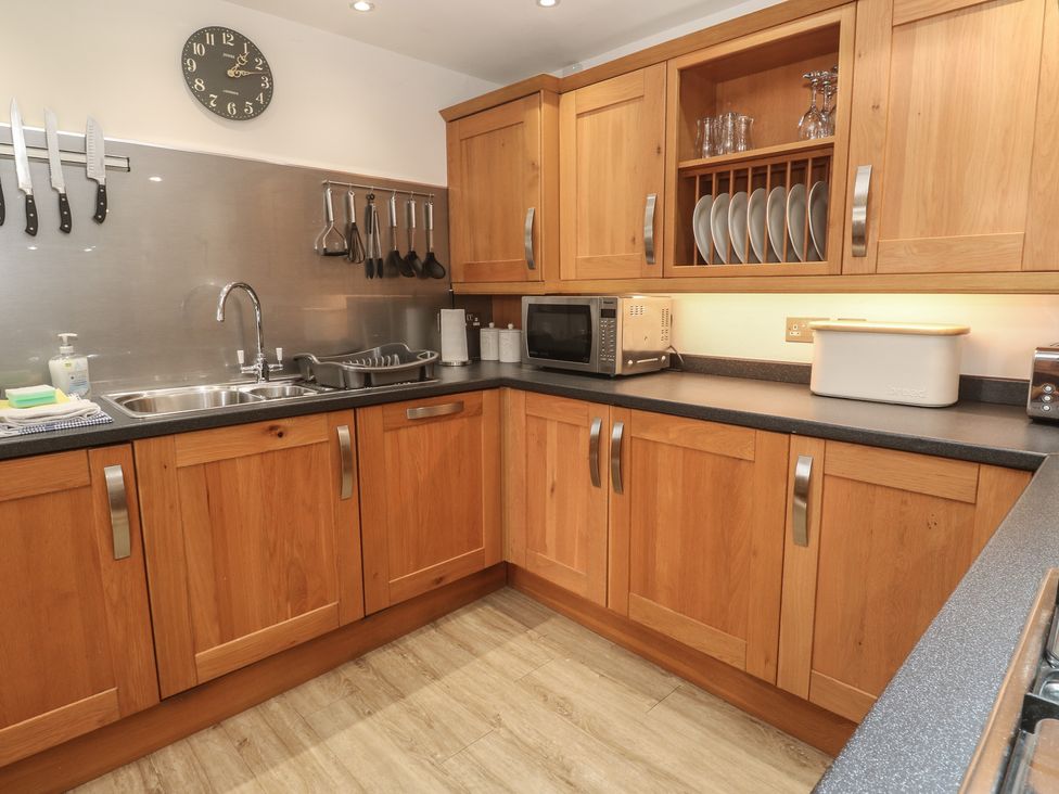 A kitchen with wooden cabinets and a stainless steel sink at Ash Barn in Falmouth
