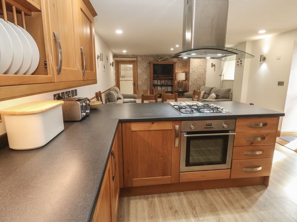 A kitchen with wooden cabinets and appliances at Ash Barn in Falmouth