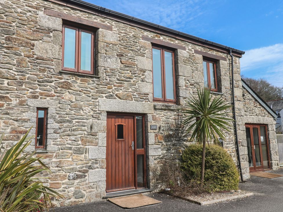 A stone house exterior with windows and a door at Ash Barn in Falmouth