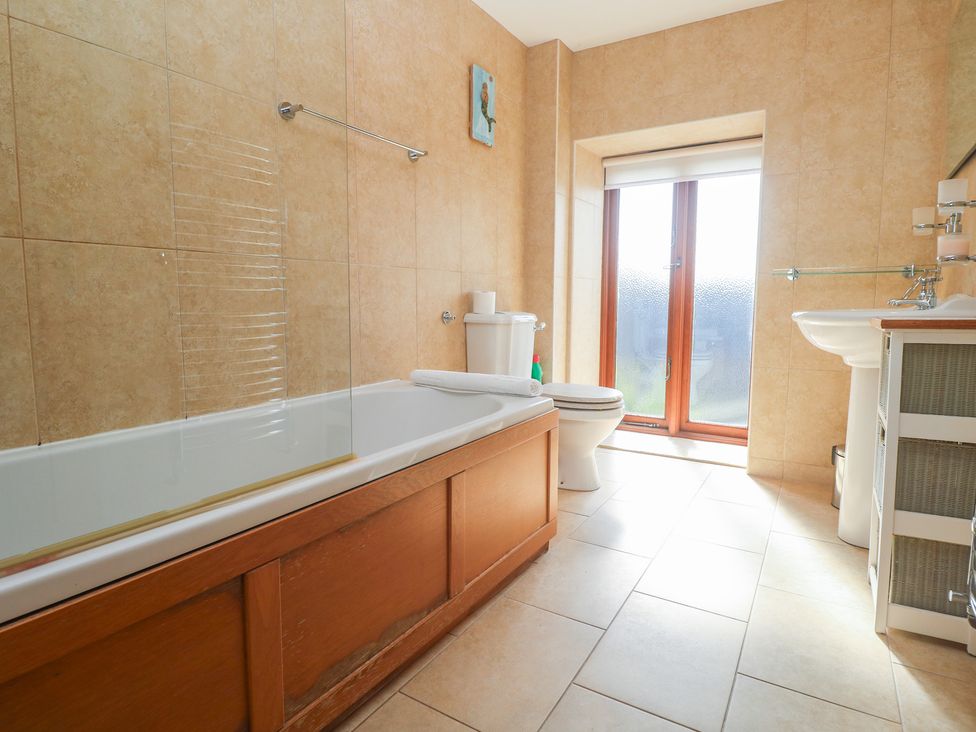 A bathroom with a bathtub, toilet, and sink at Ash Barn in Falmouth