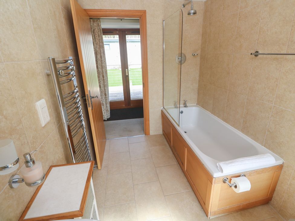 A bathroom with a bathtub and towel rail at Ash Barn Falmouth