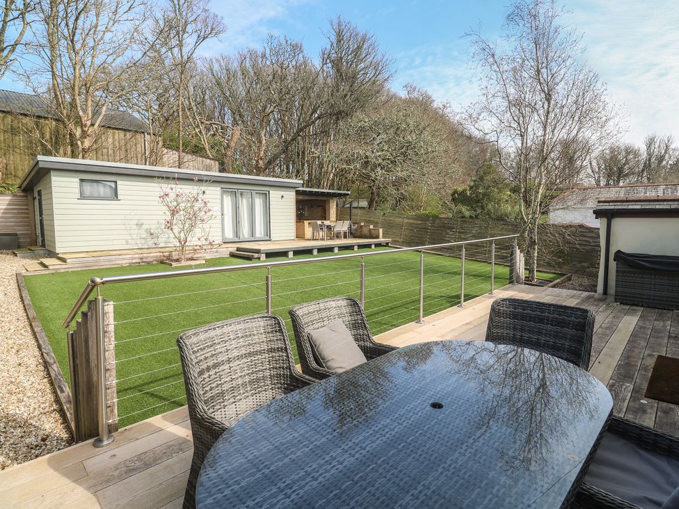 A garden with a table and chairs overlooking a building at Ash Barn in Falmouth
