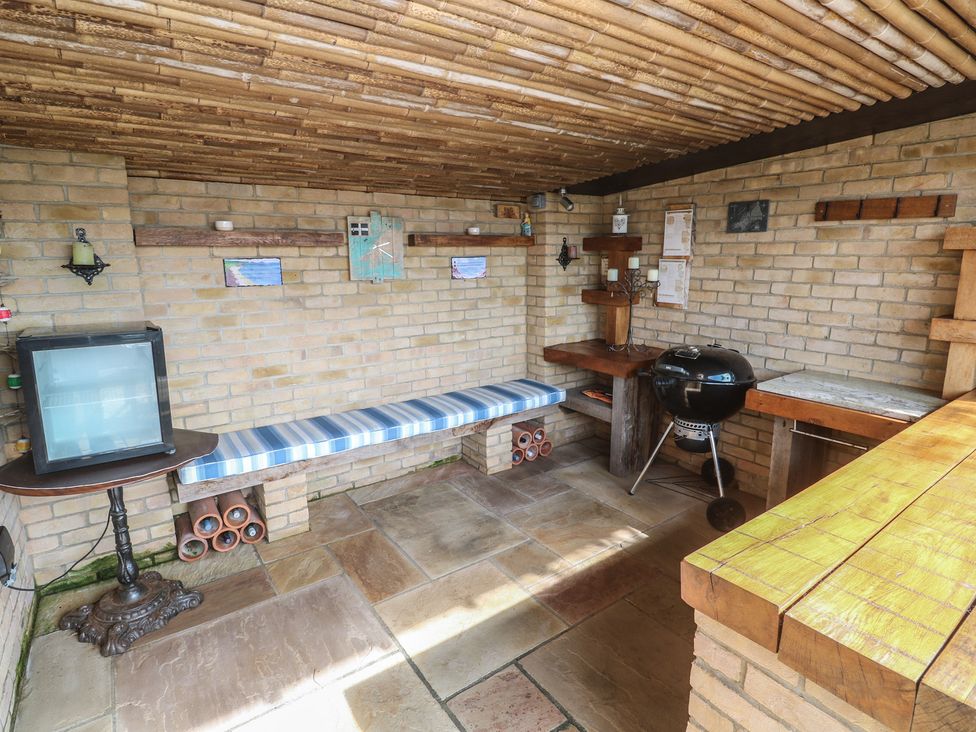 A room with a television, bench and grill at Ash Barn in Falmouth