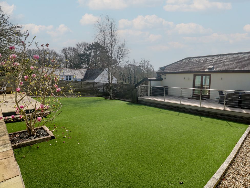 A garden with artificial grass and a flowering plant at Ash Barn in Falmouth