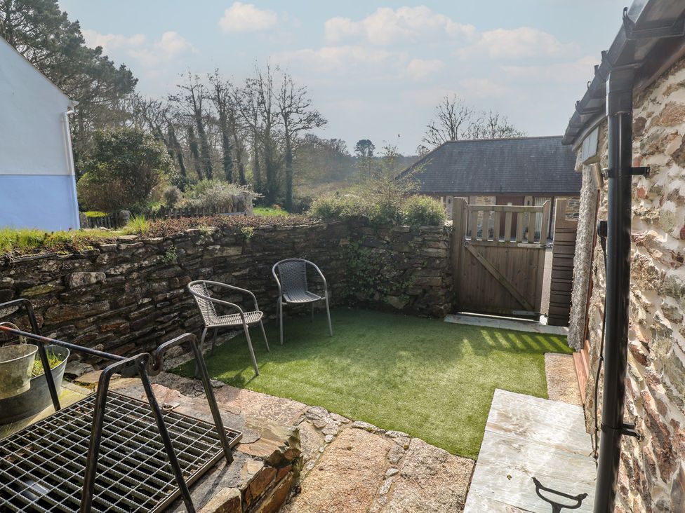 A garden area with chairs and a stone wall at Ash Barn in Falmouth
