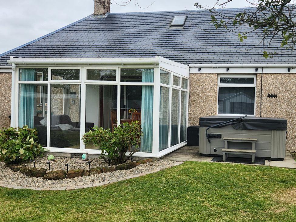 A conservatory with a sofa and a hot tub at Largieholm in Mauchline