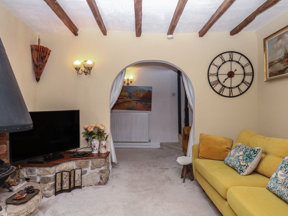 A living room with a television and yellow sofa at Mei Cottage in Pinhoe