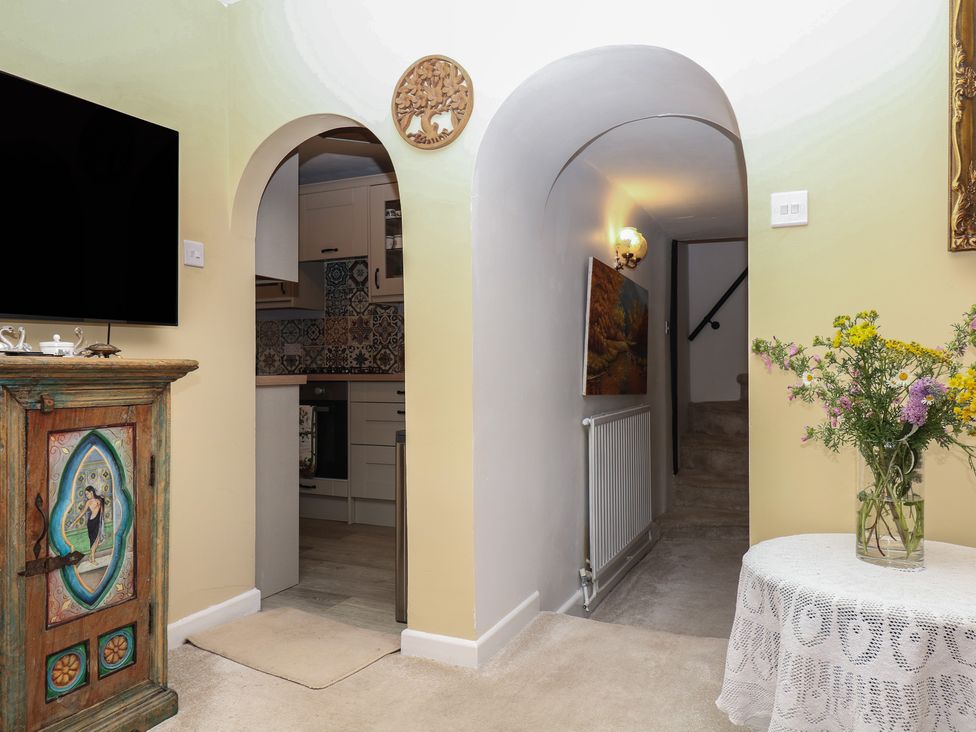 A living room with a television and a decorative cabinet at Mei Cottage Pinhoe