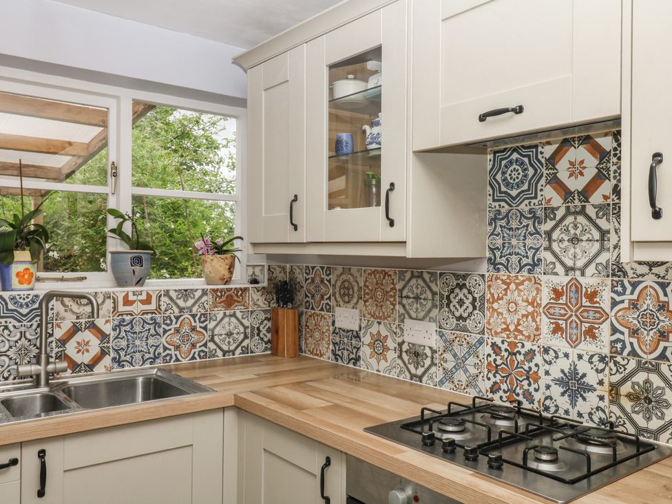 A kitchen with a sink and gas stove at Mei Cottage in Pinhoe