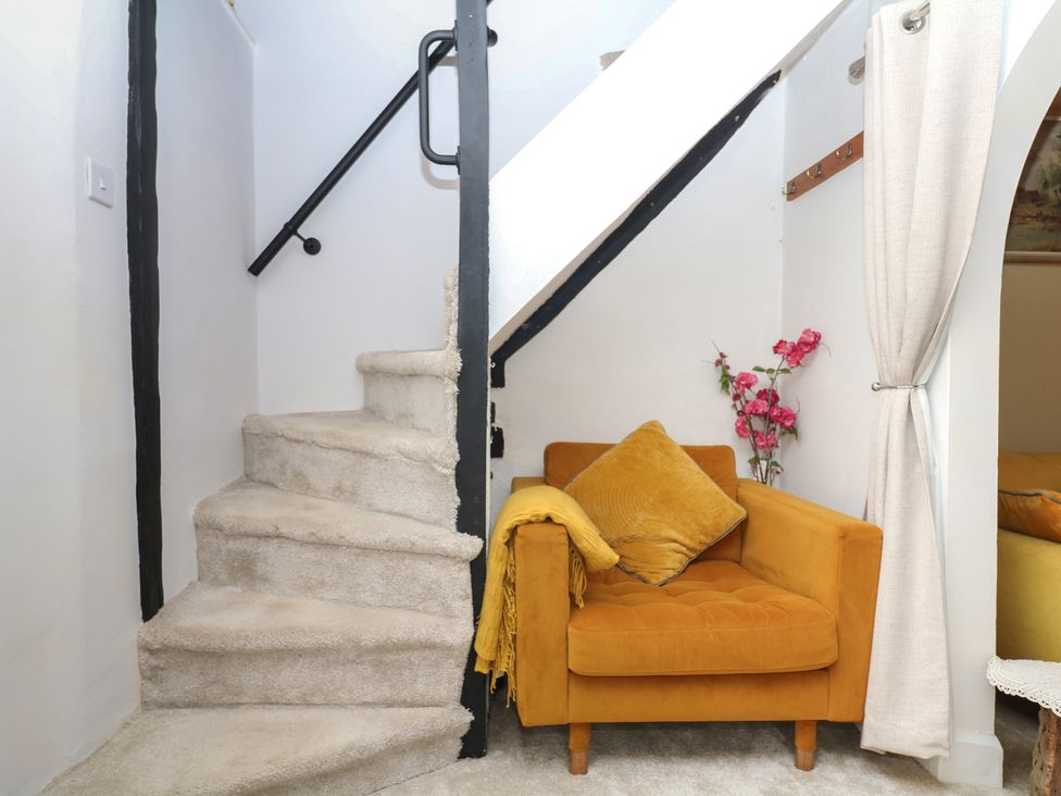 A staircase with an armchair and flowers at Mei Cottage in Pinhoe
