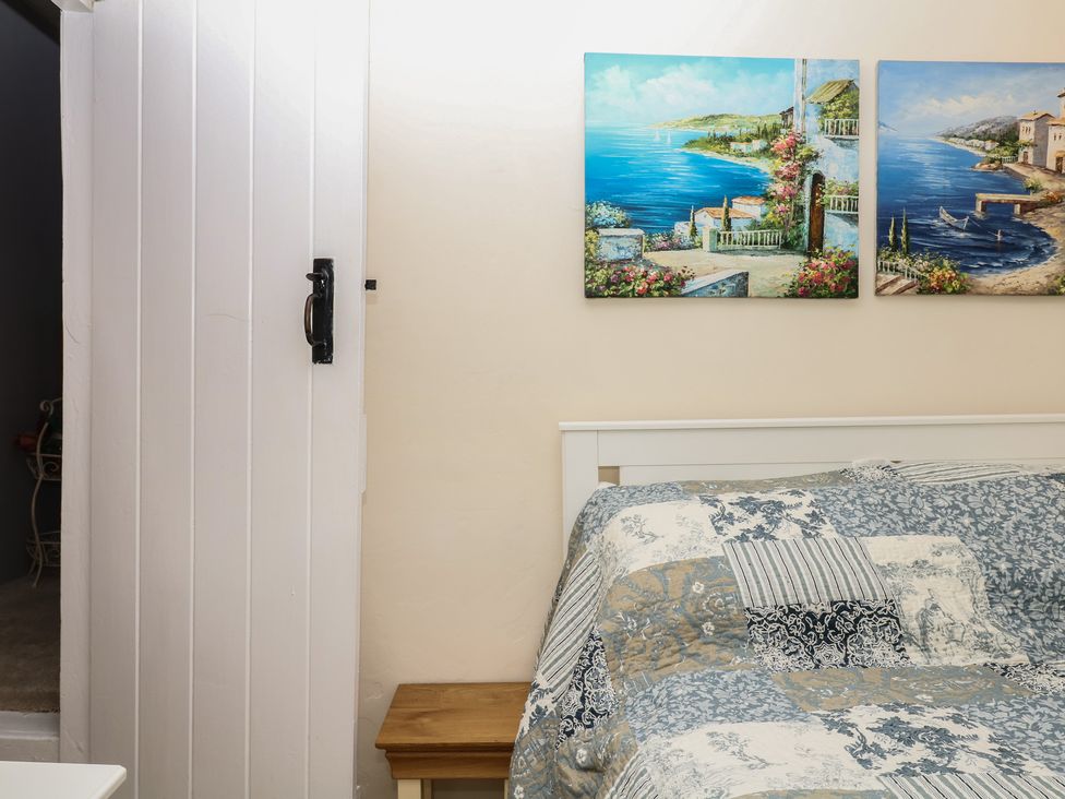A bedroom with a bed and door at Mei Cottage in Pinhoe