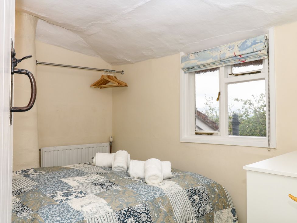 A bedroom with a bed and window at Mei Cottage in Pinhoe