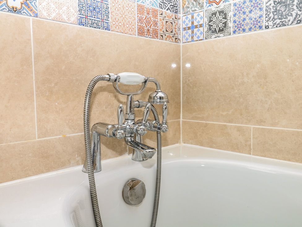 A bathtub with a faucet and showerhead at Mei Cottage in Pinhoe