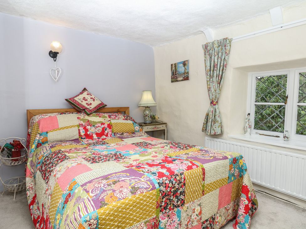 A bedroom with a large bed and a window at Mei Cottage in Pinhoe
