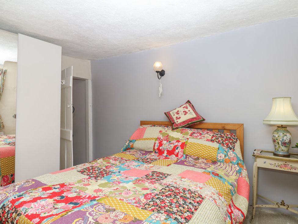 A bedroom with a bed and side table at Mei Cottage in Pinhoe