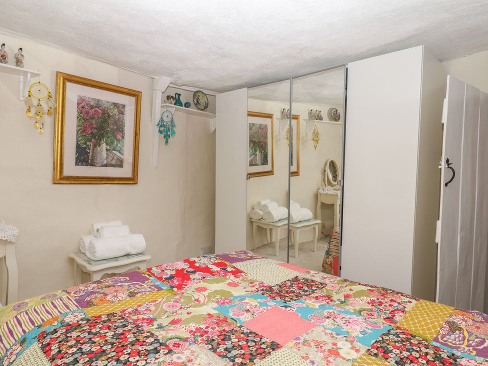 A bedroom with a bed and wardrobe at Mei Cottage in Pinhoe