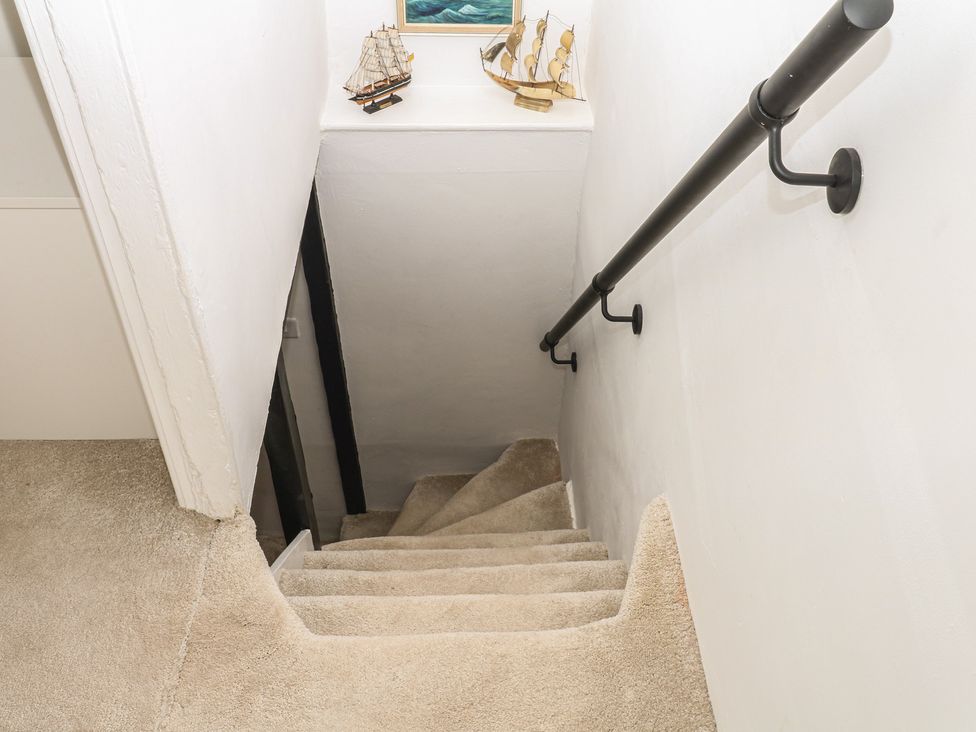 A staircase with light-colored carpet and boat models at Mei Cottage Pinhoe