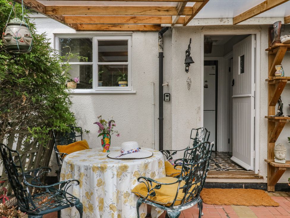 An outdoor seating area with a table and chairs at Mei Cottage in Pinhoe