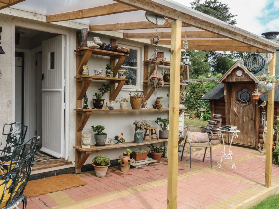 An outdoor area with shelves holding plants and a garden shed at Mei Cottage in Pinhoe