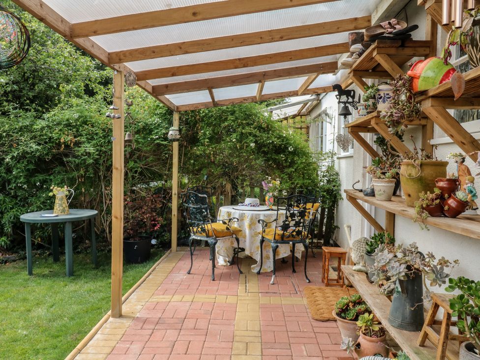 A garden area with a table and chairs at Mei Cottage in Pinhoe