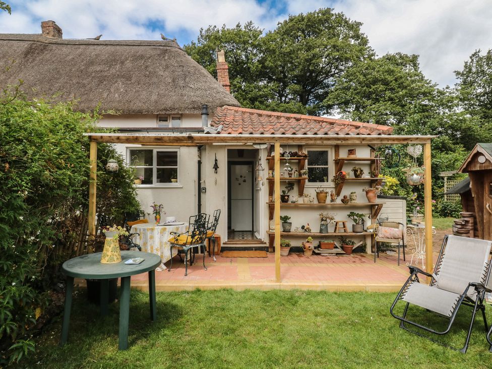 A garden with a house and patio furniture at Mei Cottage Pinhoe