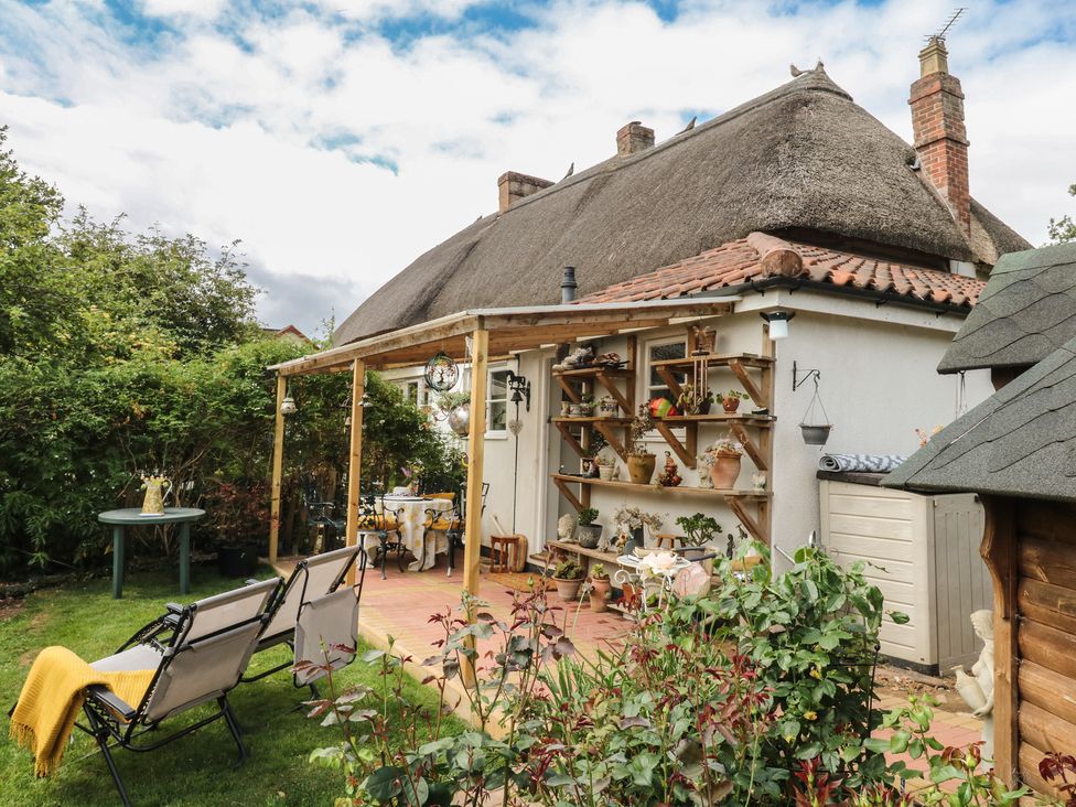 A garden with a seating area and plants at Mei Cottage in Pinhoe