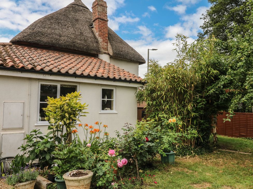 A house with a thatched roof and a garden at Mei Cottage in Pinhoe