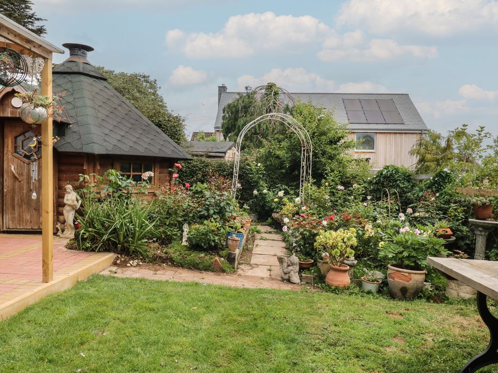 A garden with shed and flower beds at Mei Cottage in Pinhoe