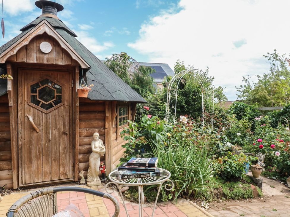 A garden with a shed flowers and a table with books at Mei Cottage in Pinhoe