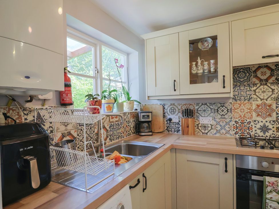 A kitchen with a sink and dish rack at Mei's Cottage in Pinhoe