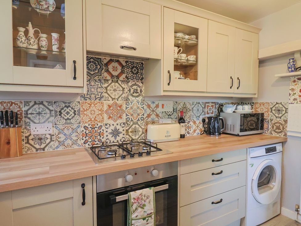 A kitchen with cabinets, stove, toaster, microwave at Mei's Cottage in Pinhoe