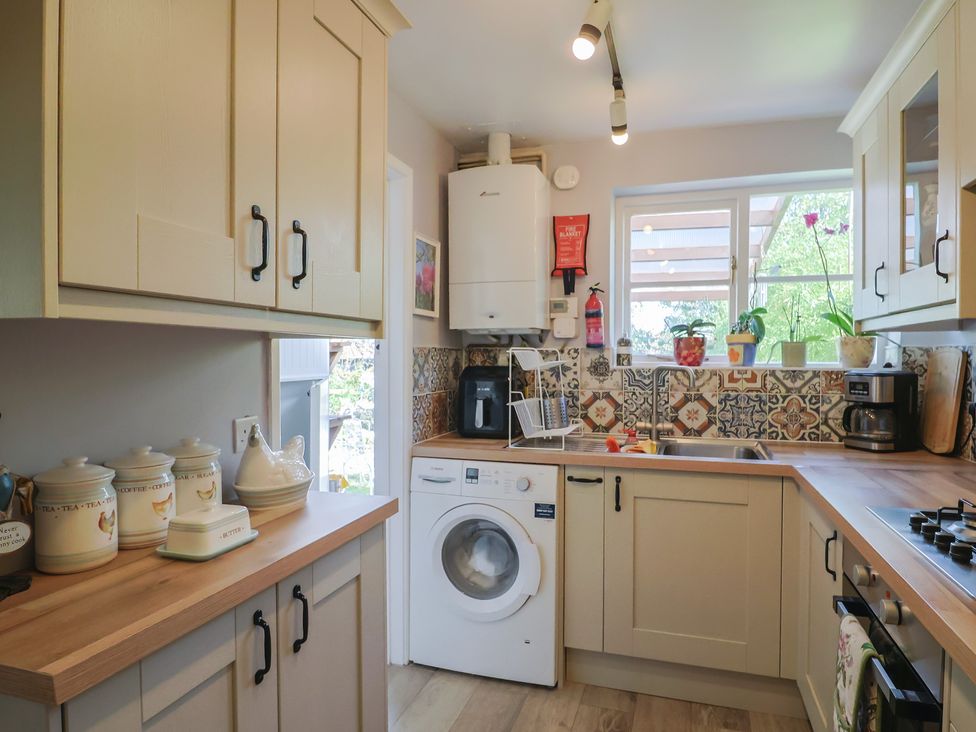 A kitchen with cabinets and appliances at Mei's Cottage in Pinhoe