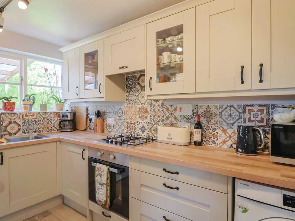A kitchen with cabinets and appliances at Mei's Cottage in Pinhoe