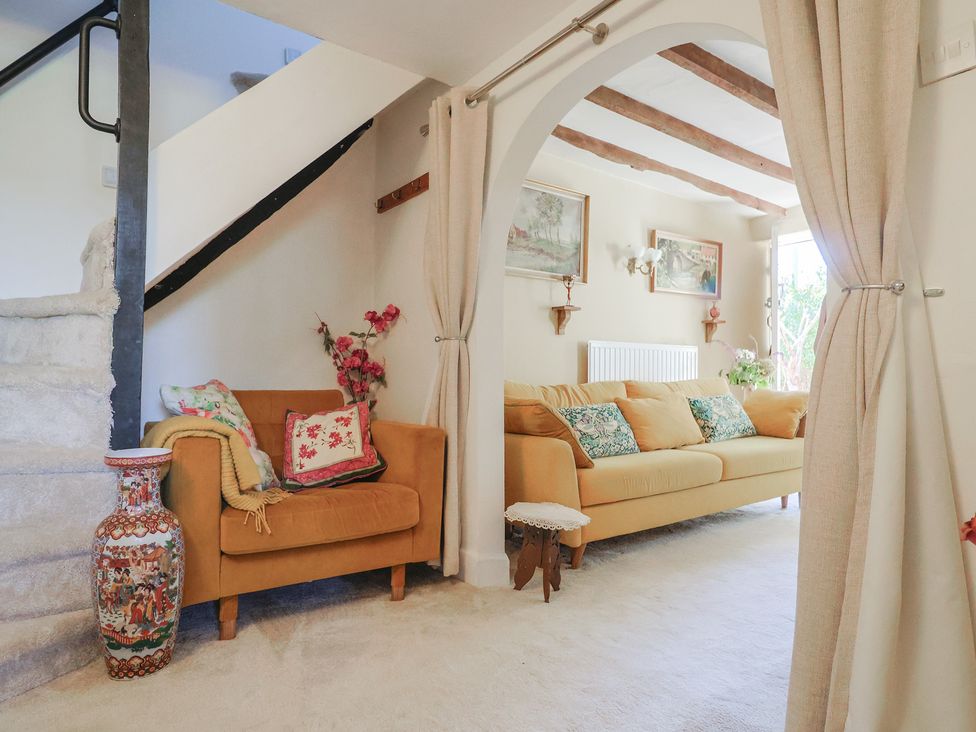 A living room with a sofa, chair, and staircase at Mei's Cottage in Pinhoe