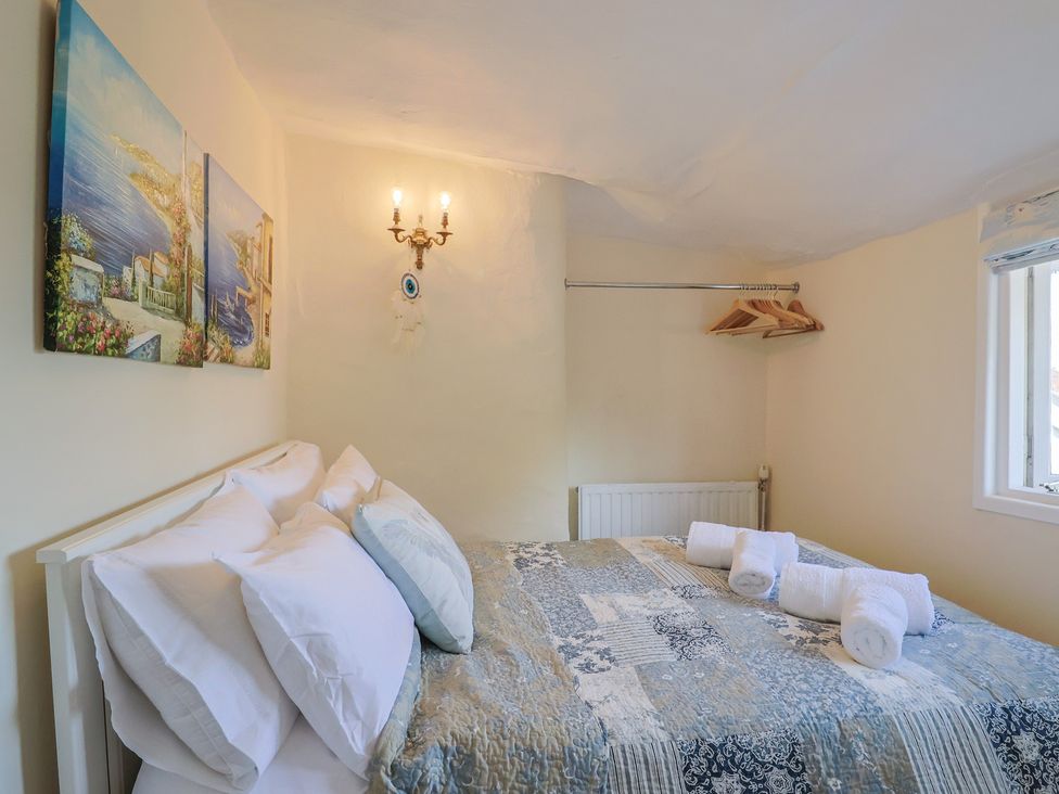 A bedroom with a bed and art on the wall at Mei's Cottage in Pinhoe