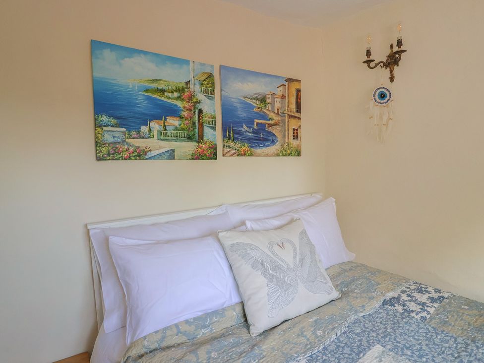 A bedroom with a bed and wall art at Mei's Cottage in Pinhoe