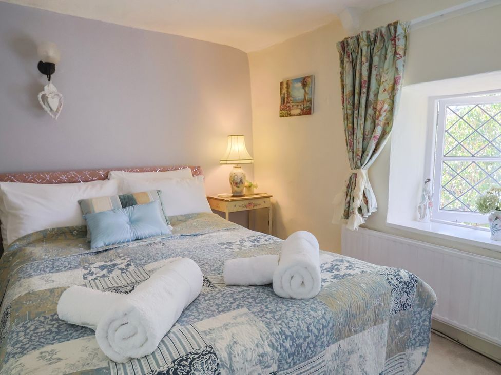 A bedroom with a bed and bedside table at Mei's Cottage in Pinhoe