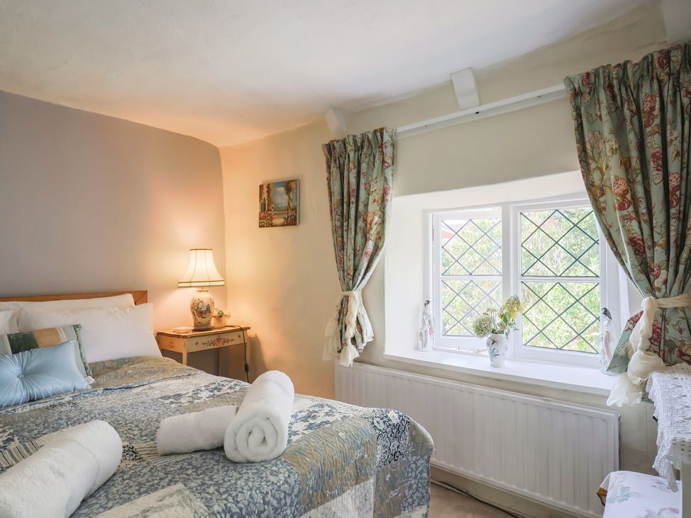 A bedroom with a bed and window at Mei's Cottage in Pinhoe