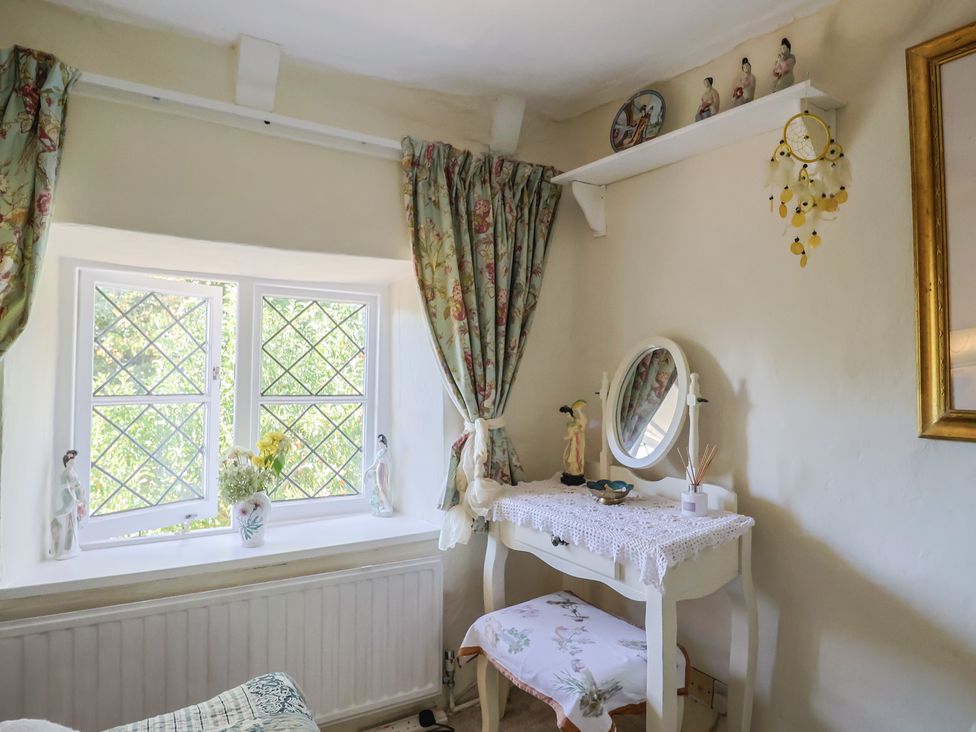A bedroom with a mirror and dresser at Mei's Cottage in Pinhoe
