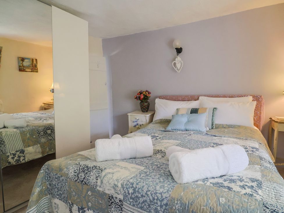 A bedroom with a bed and bedside table at Mei's Cottage in Pinhoe