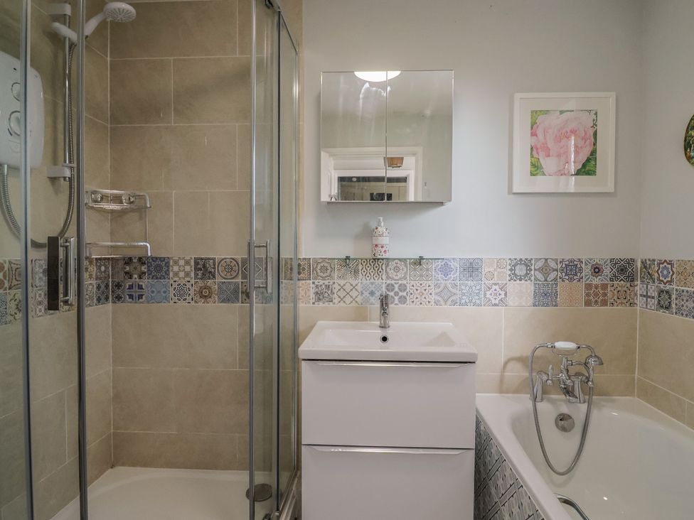 A bathroom with a shower, bathtub, and sink at Mei's Cottage in Pinhoe