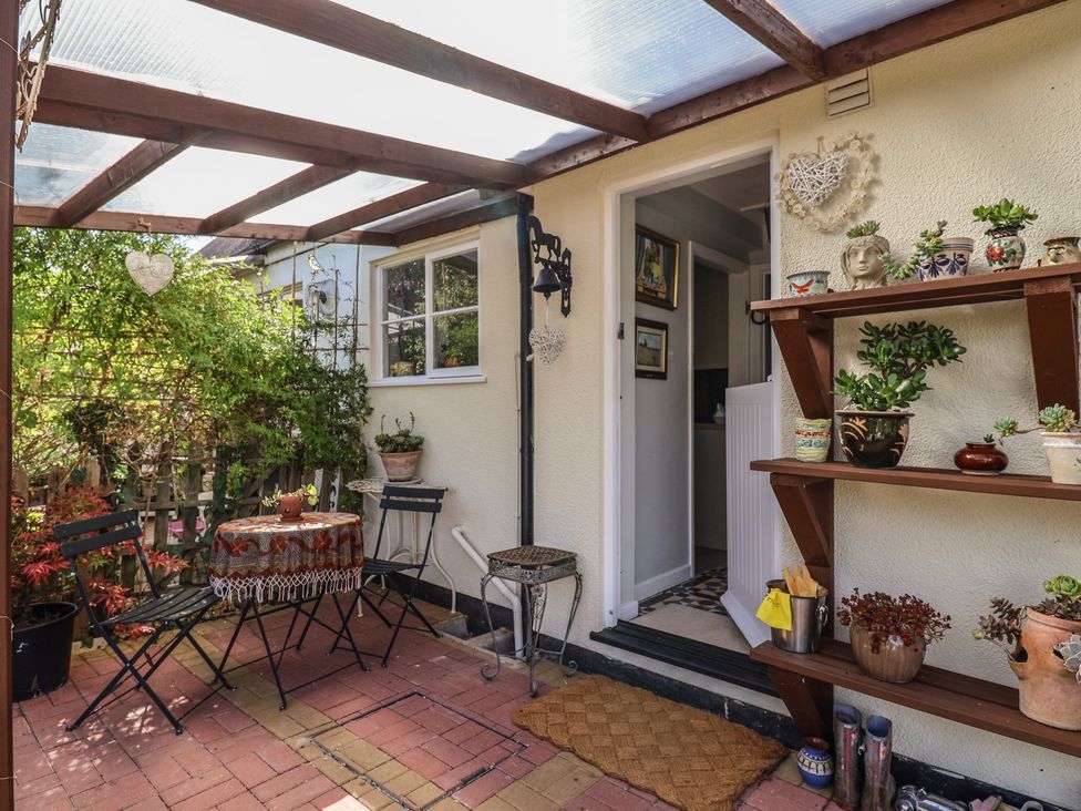 An outdoor patio with a table and chairs at Mei's Cottage in Pinhoe
