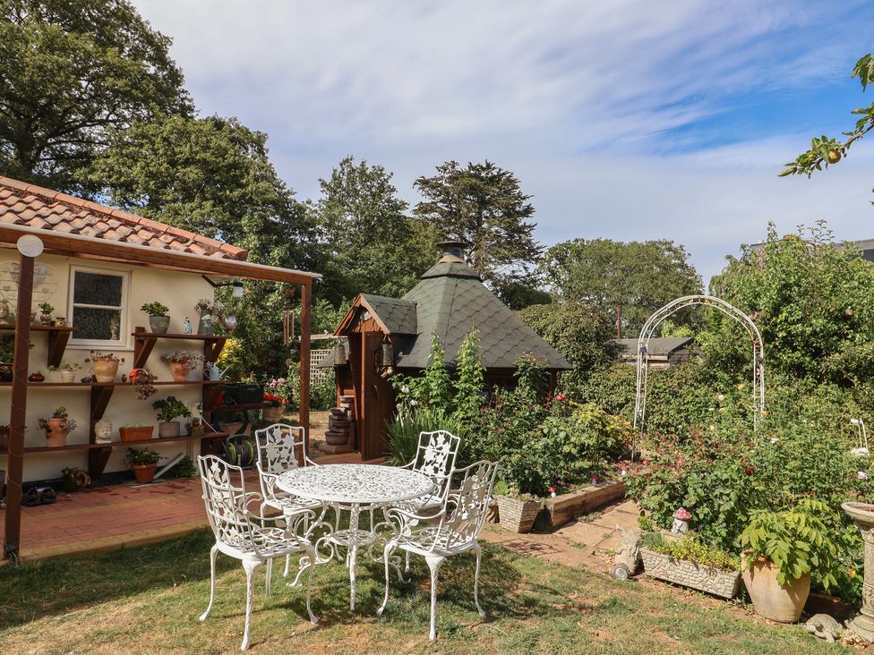 A garden with a table and chairs at Mei's Cottage in Pinhoe