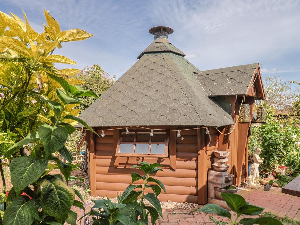 A log cabin with a sloped roof in a garden at Mei's Cottage in Pinhoe