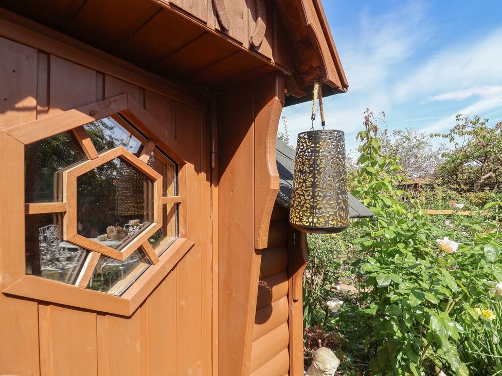 A wooden cabin with an octagonal window and lantern in the garden at Mei's Cottage in Pinhoe