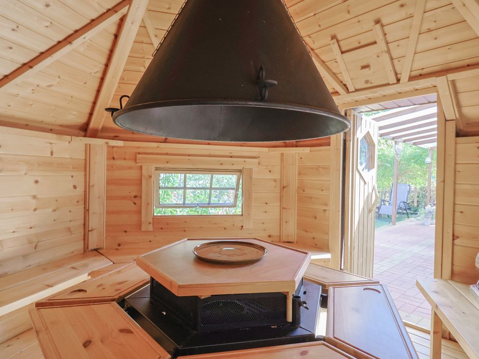 A room with wooden walls and a central stove at Mei's Cottage in Pinhoe